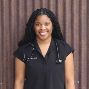 Dr. Alexis Allen, woman smiling outside against wall