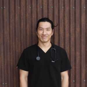 Dr. Juhwan Kim, man smiling outside against wall